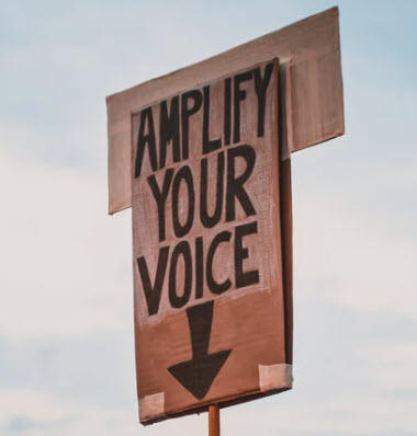 a board saying amplify your voice