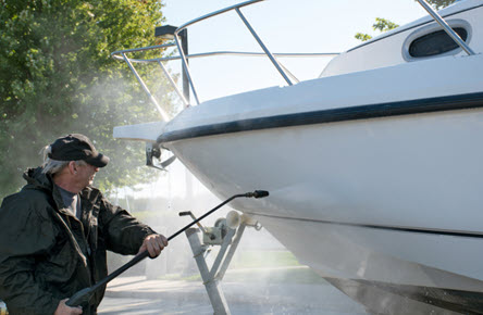 a person using a pressure washer to clean their boat